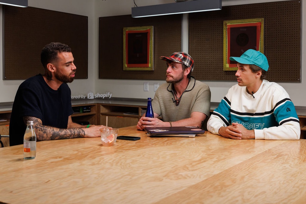 Dom and Benza talking around a big wooden table at Shopify